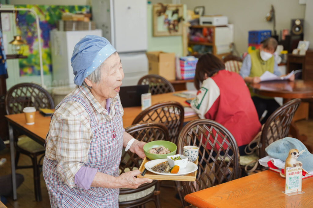 ばあちゃん喫茶で料理を提供するおばあちゃん