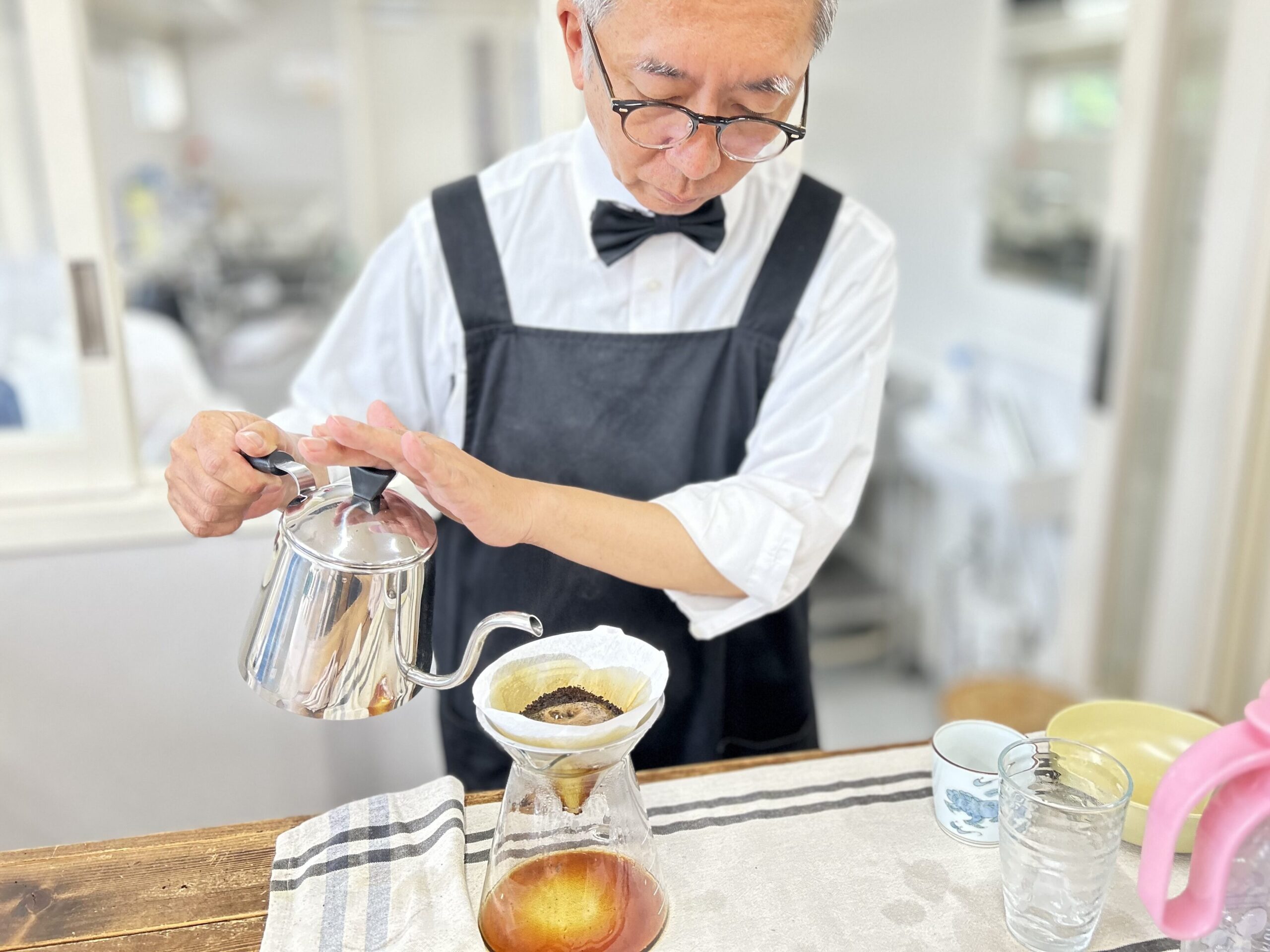 明るい部屋でコーヒーを注ぐおじいさん。コーヒーを嗜むおじいさん。 明るい部屋でコーヒーを注ぐおじいさん。コーヒーを嗜むおじいさん。