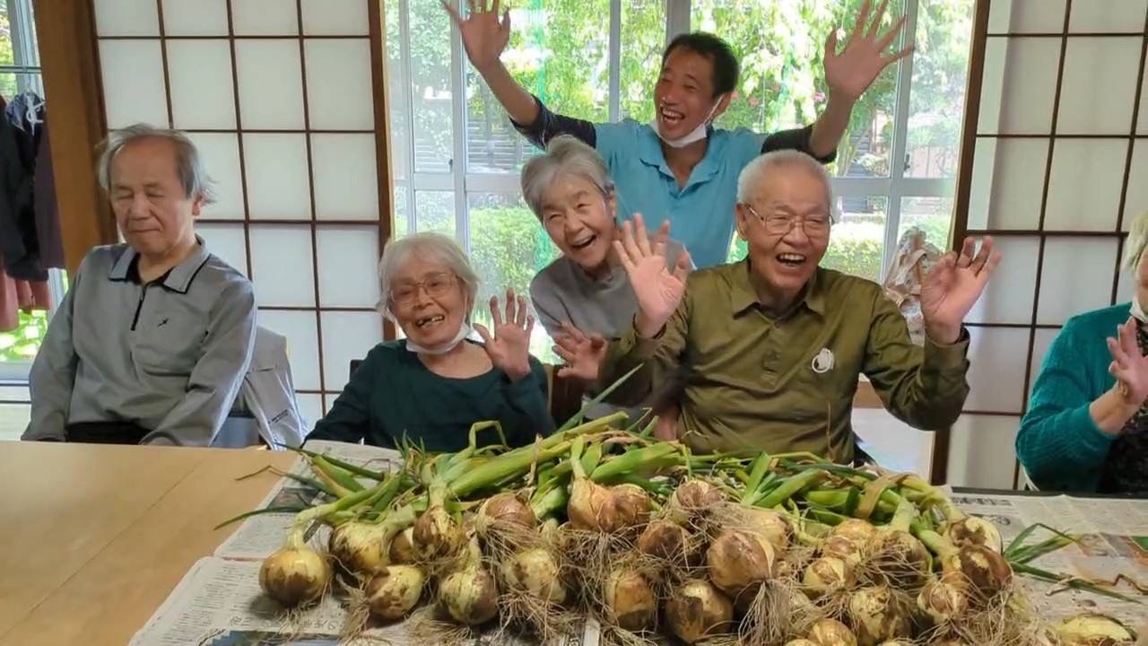 みんなで収穫した玉ねぎと一緒に、笑顔あふれるシニアと介護スタッフ