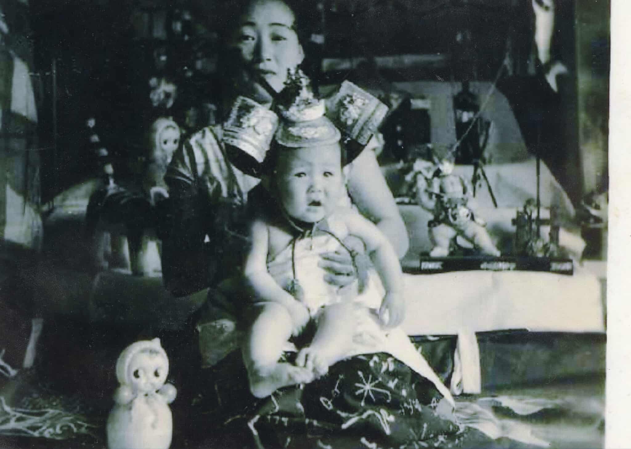 昭和の時代の初節句で母に抱えられる赤ん坊の白黒写真