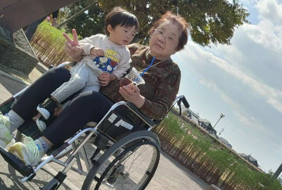 小さい子どもを膝の上で抱く車椅子のおばあちゃん