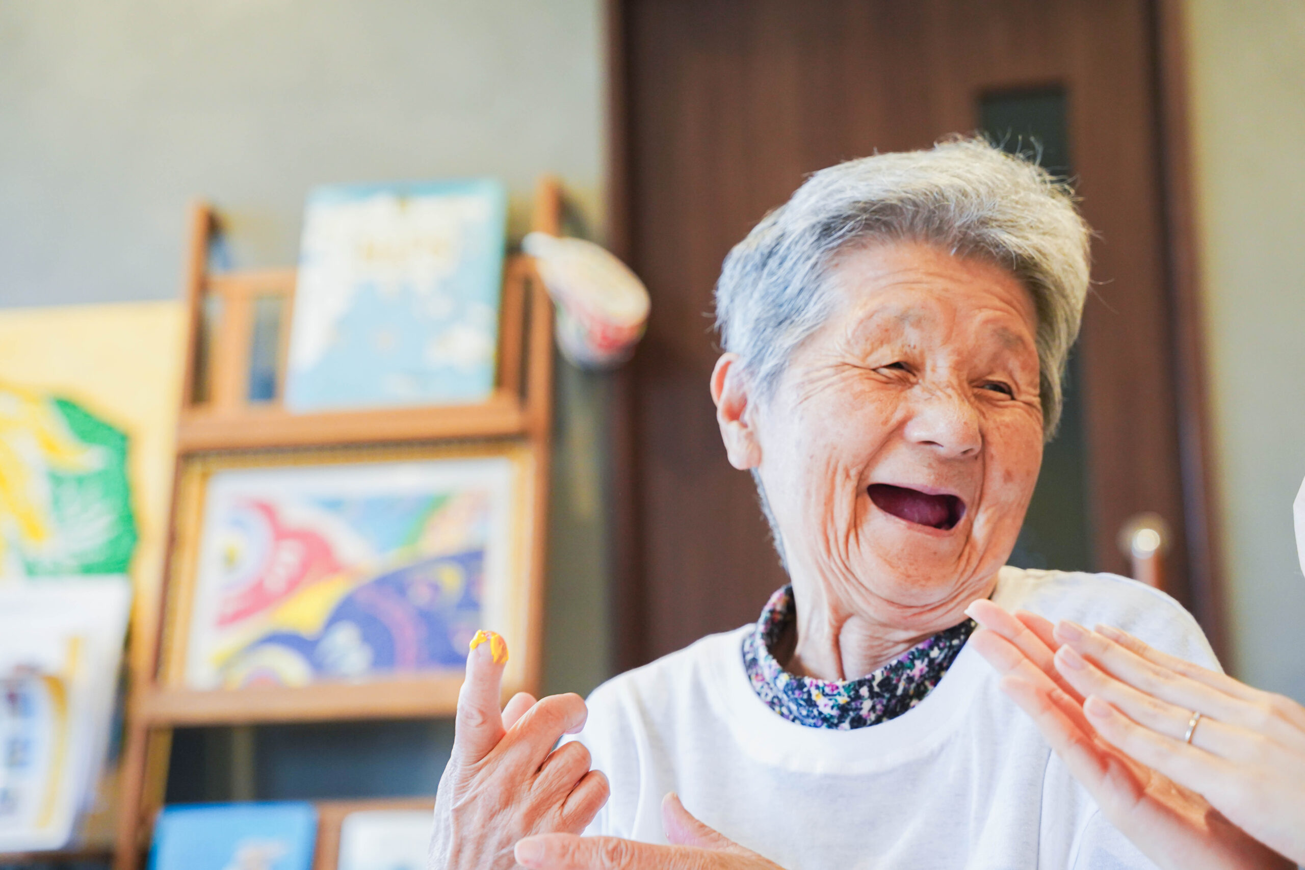 指に付いた黄色い絵の具で笑顔が弾ける素敵なおばあちゃん