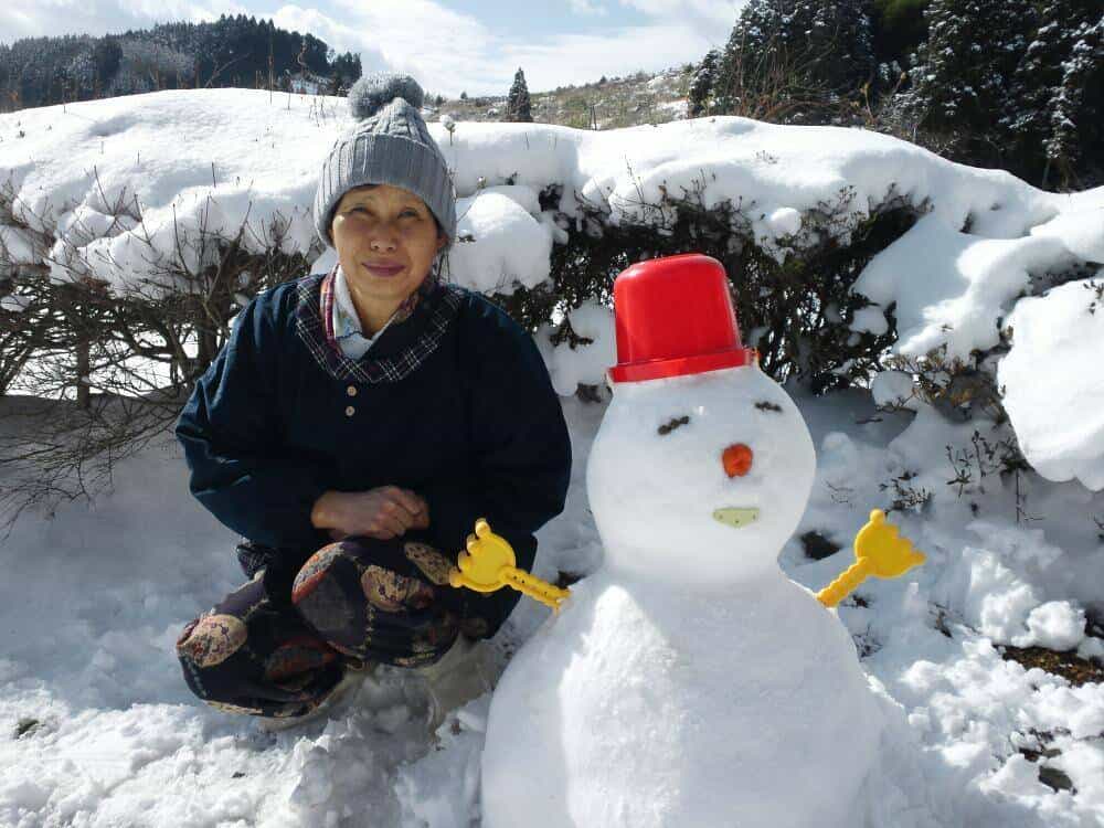 手作り雪だるまの隣で微笑むばあちゃん